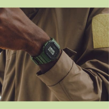 relogio-casio-gshock-DW-5610UU-3_2 Foto do relógio Casio G-Shock DW-5610UU-3 verde-oliva original com caixa quadrada, bisel bicolor em camadas e display digital para uso masculino casual e esportivo.