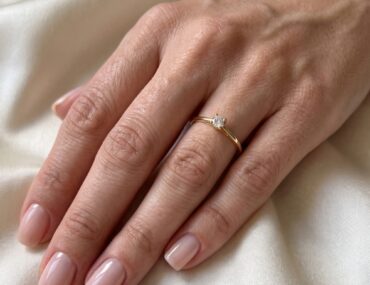 Anel solitário de ouro com brilhante de 7 pontos usado na mão feminina